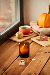 season and objects concept - candle and matches in matchbox on window sill in autumn