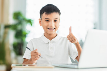 Boy using tablet and laptop.Study online class.Showing thumb up.