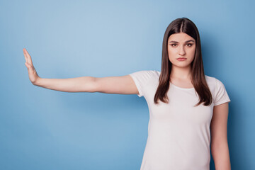 Portrait of serious focused strict lady raise palm show ban gesture on blue background