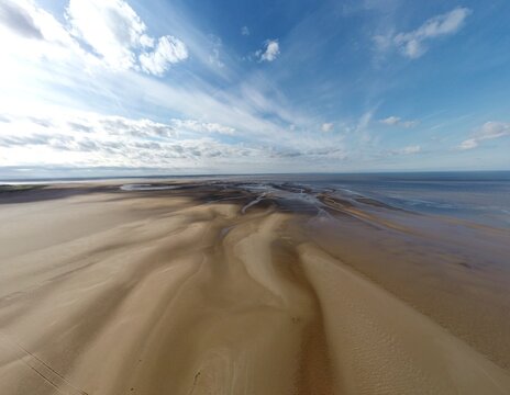 Drone image of a sandy beach with blue sea and a blue sky background. Taken in Lytham England. 