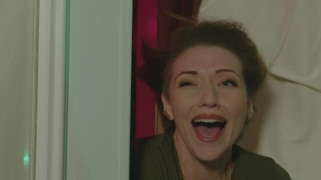 A woman opens a door and is seen screaming. The background is glowing along with wind blowing in the woman's face.