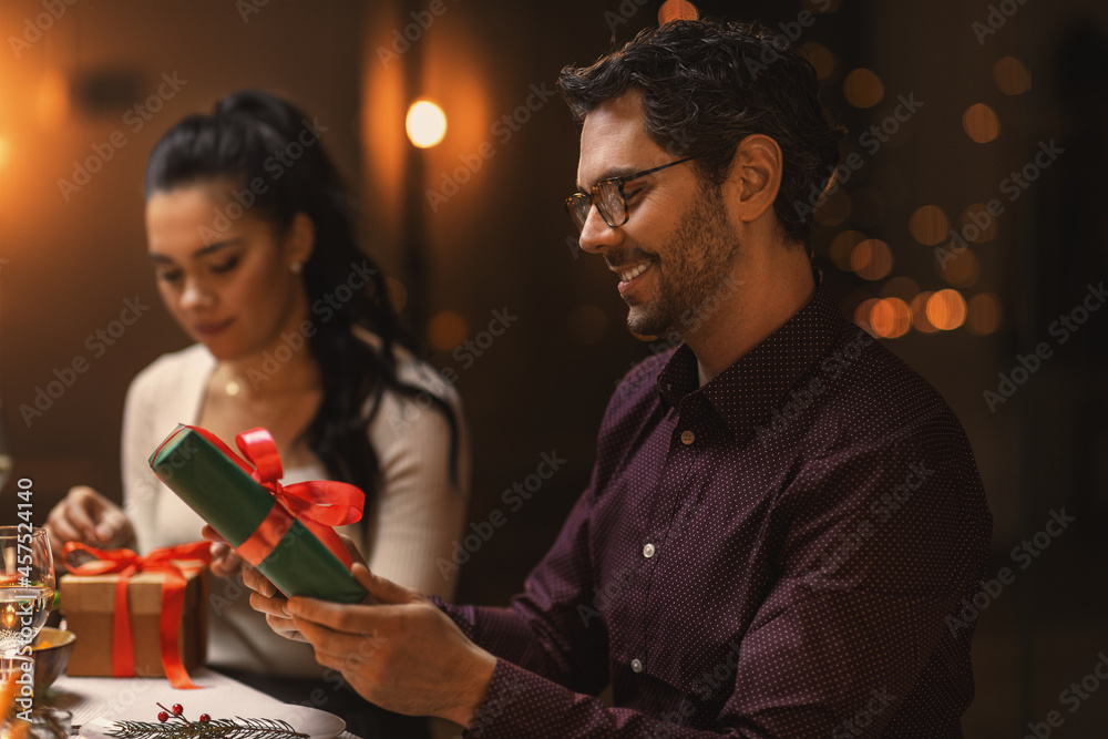 Poster holidays, party and celebration concept - happy smiling man with gift box on christmas dinner at hom