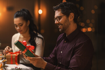 holidays, party and celebration concept - happy smiling man with gift box on christmas dinner at home