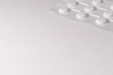 White pack of tablets on a white background. A packet of tablets is placed in the corner of the photo. Free space for text, copy space