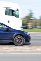 View of a blue car from the side, a fast driving car in traffic. Motion blur.
