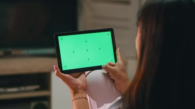Anonymous woman swiping pictures on tablet