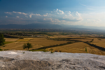 トルコ　ヒエラポリス・パムッカレの白い鍾乳石に咲いた花と石灰華段丘から望む風景