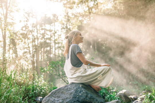 Profile of a woman sitting in the jungle illuminated by the rays of the sun
