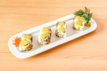 Sushi uramaki california roll with sesame and poppy seeds, yellow cream, salmon and wasabi with fresh dill