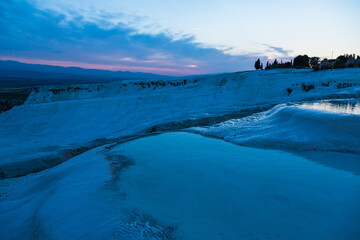 トルコ　夕暮れ時のヒエラポリス・パムッカレの石灰棚と青い水面