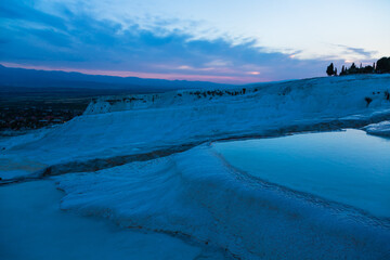 トルコ　夕暮れ時のヒエラポリス・パムッカレの石灰棚と青い水面