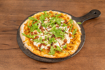 Vegan pizza with potato cheese, arugula, raisins, dehydrated tomato and black tray
