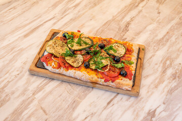Vegan pizza with tomato, whole black olive, cherry tomato, zucchini slices, seaweed and oregano with white onion