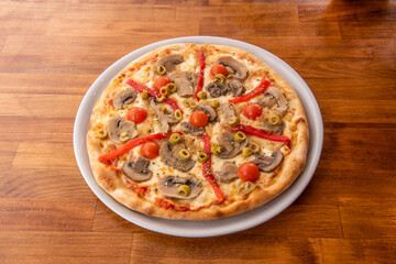 Vegan pizza with roasted peppers, potato cheese, whole cherry tomatoes, mushroom slices, white onion, green olives and tomato sauce