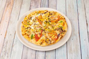 Vegetable pizza with potato cheese, sweet corn, red onion, crumbled tomato, red onion, slices of mushrooms and oregano