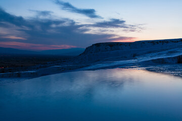 トルコ　夕暮れ時のヒエラポリス・パムッカレの石灰棚と青い水面