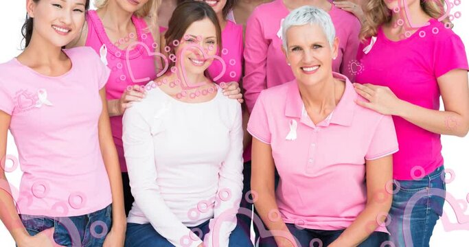 Animation of pink hearts floating over diverse group of smiling women in pink with cancer ribbons on
