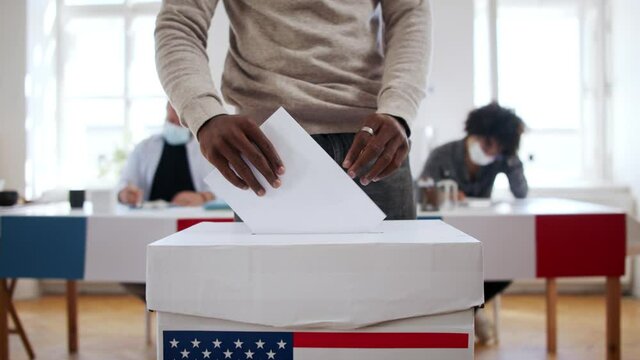 unrecognizable african american man putting his vote in the ballot box usa election