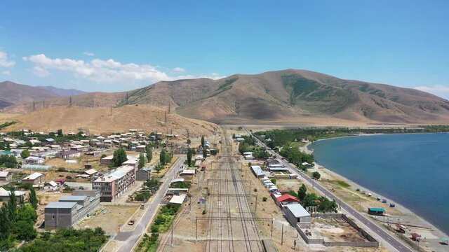  Aerial view Railway line near lake. Empty  train lines in Sevan town. Famous lake Sevan, in Armenia. Aerial footage railway near highway, traffic, street. Discovery Armenia. Touristic place.