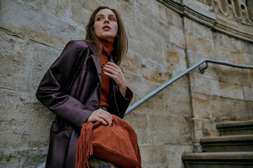 Autumn fashion conception: elegant confident woman wearing trendy leather coat, turtleneck, holding...