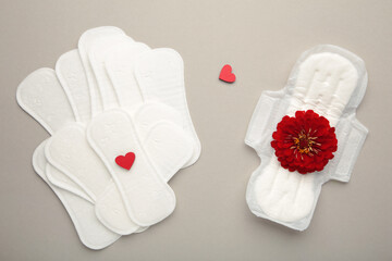 Menstrual pads on a grey background. Menstruation cycle. Hygiene and protection. A rose flower lies on a menstrual pad.