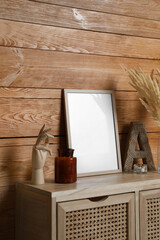 Empty frame with other decor on table near wooden wall. Mockup for design