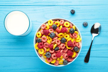 Breakfast with corn flakes, milk and berry on blue background.
