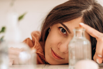 Portrait of a beautiful young woman of mixed race, covering her face with a glass vase.