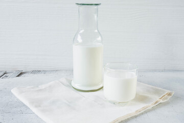 milk in glass and milk bottle on white wooden background