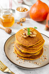 Pumpkin pancakes in a ceramic plate on a light gray culinary background close-up