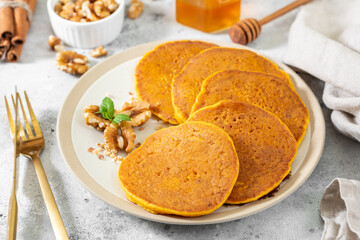 Pumpkin pancakes in a ceramic plate on a light gray culinary background close-up