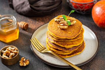 Pumpkin pancakes in a ceramic plate on a dark background close-up