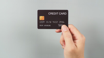 Hand is holding black credit card isolated on grey background...