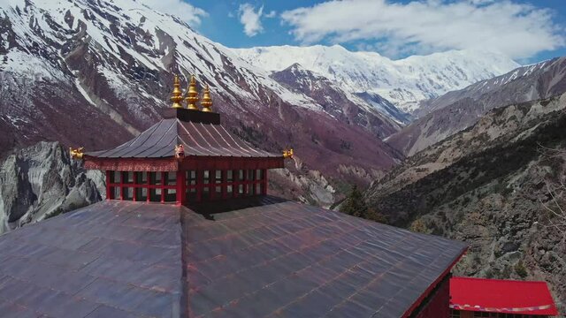 Aerial flight above red pagoda, wonderful snowy highlands panorama with white Tilicho Peak, Nepal
