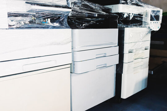Copy machines, packed in clear plastic, which have been repaired until they can be used again, are arranged in a warehouse ready to be delivered to customers for use again.