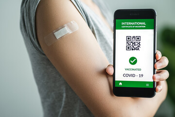 young women showing adhesive plaster her on arm her vaccinated and app mobile digital screen vaccinated COVID-19 or coronavirus certificate, immunity vaccine concept.