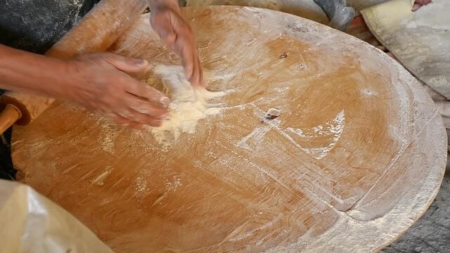 Close-up hands of woman preparing dough for Armenian traditional bread called Lavash on wooden board