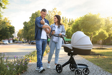 Happy parents walking with their baby in park on sunny day