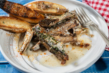 Plate of sardines in oil with parsley and paprika with some toasts on a rustic wooden table.
