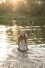The girl is standing in the river and splashing water
