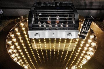 Powerful compact tube amplifier over infinity. A coffee table with lamp lighting as space. Warm...