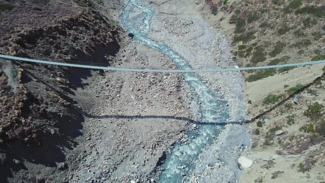 Suspension bridge hanging above Khola Ghyanchang River gorge near snowy Annapurna mountain, nearby Ledar and Yak Kharka villages, Nepal