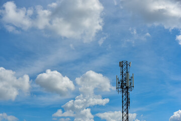 Telecommunication towers with clouds on blue sky background.