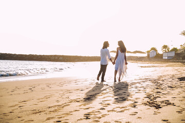 Beautiful couple in love walking on the tropical beach, enjoying honeymoon and summer holidays.