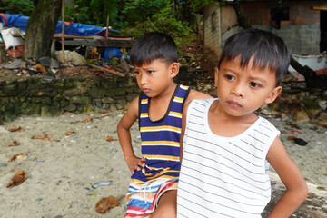 Fishing village boys waiting on the beachfor grandfather to return from fishing. A traditional fishing family net fishing from their banka boat at  bignayan village, Philippines