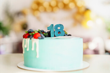 Festive background. A cake with fruit and chocolate numbers 18, blue color is on the table against the background of the decorated room. A holiday card. A sweet treat. Birthday cake.