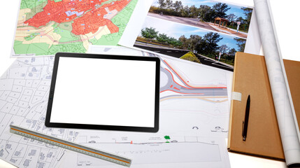 Urbanisme - Aménagement du territoire - Tablette numérique et cartes de plan de masse d'un projet de voirie et giratoire posé sur un bureau