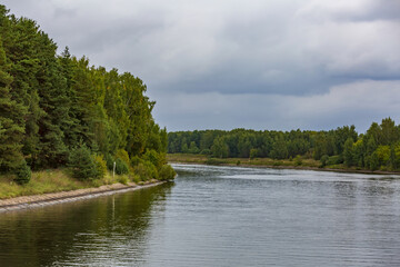 Scenic river landscape with green trees in early autumn