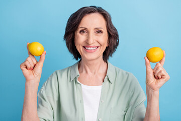 Photo portrait senior woman keeping lemons smiling happy isolated pastel blue color background