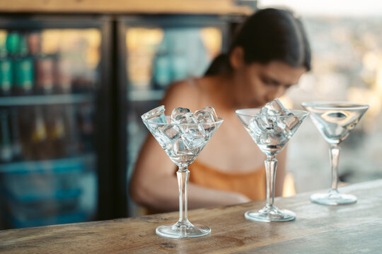 Female barkeeper making cocktails with ice cubes